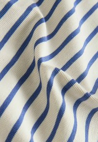 Tissu doux tissé avec des rayures horizontales bleu marine sur fond blanc cassé, présentant de légers plis et une texture délicate.