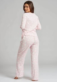 Pink pajama set made of soft fabric, featuring a long-sleeve top and loose-fitting pants with a star pattern throughout.