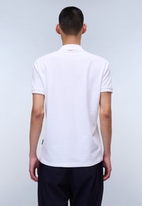 Polo shirt blanc à manches courtes, col côtelé et ourlet droit. Les détails notables incluent un petit logo et des coutures contrastantes à l'arrière.