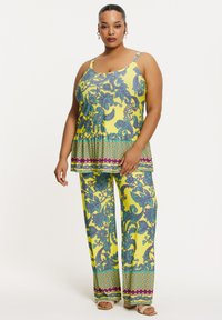 Gelbes, gemustertes Zweiteiler-Outfit mit einem Peplum-Top, das blau-lila florale Designs zeigt, und lockeren Hosen mit passenden Mustern.