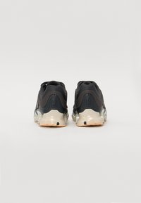 Czarne buty sportowe z teksturowaną cholewką, amortyzowaną podeszwą i przezroczystymi elementami, beżową podeszwą zewnętrzną oraz logo z tyłu.