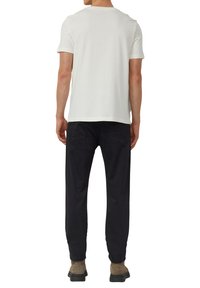 Biała koszulka z krótkim rękawem wykonana z bawełny. Widok od tyłu ukazuje prosty krój z okrągłym dekoltem bez widocznych wzorów czy logo.