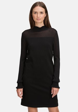 Sort kjole med en transparent, tekstureret overdel og fast bund. Lange ærmer med flæsekant, tætsiddende silhuet og rund halsudskæring.
