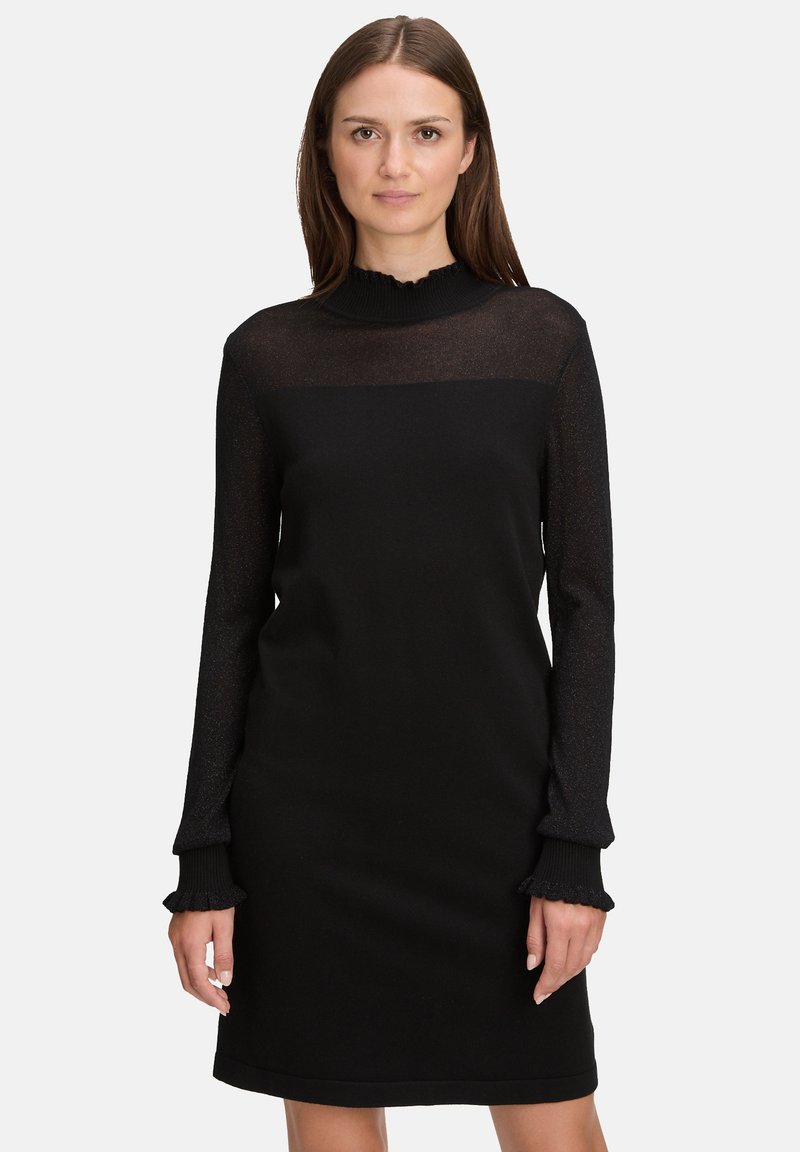 Czarna sukienka z przezroczystą, teksturowaną górą i gładkim dołem. Długie rękawy z falbankami przy mankietach, dopasowana sylwetka oraz okrągły dekolt.