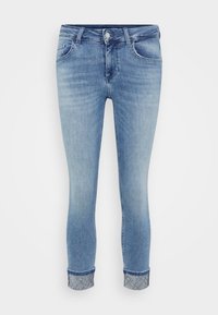 Jeans skinny in denim azzurro con risvolto. Presentano cinque tasche e un chiusura frontale con bottone. Il tessuto appare leggermente sbiadito.