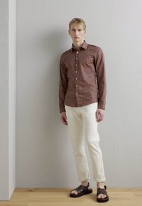 Barna mintás ing, fehér slim-fit nadrág és barna szandálok. Simaságot árasztó anyag, diszkrét pöttyös mintával, laza szabású.