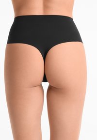 Hoge taille zwarte onderbroek van een gladde, rekbare stof. Heeft een eenvoudig ontwerp zonder patronen of zichtbare hardware.