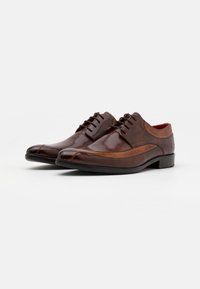 Chaussures de ville en cuir marron avec une finition polie, caractérisées par un bout arrondi, un système de laçage et des accents contrastants en tan sur le dessus.