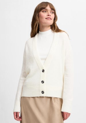 Witte gebreide cardigan met een V-hals, drie donkere knopen en geribde manchetten, met een zachte textuur en een relaxte pasvorm, gedragen over een witte top.