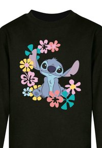 Schwarzer Sweatshirt mit einem Cartoon-Charakter, der von bunten Blumen umgeben ist. Der Charakter hat blaue Haut, große Ohren und einen verspielten Ausdruck.