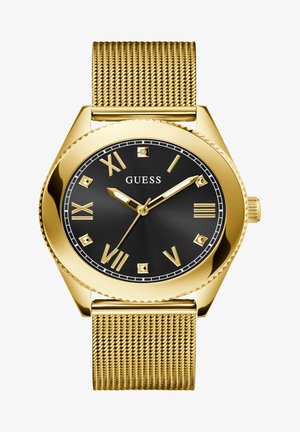 Montre avec bracelet en maille dorée, affichant un cadran noir, des index horaires en chiffres romains et des accents dorés. La lunette a un bord texturé.