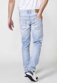Vaqueros de denim de color azul claro con un corte recto, dos bolsillos traseros, costuras visibles y una etiqueta de cuero de la marca en la cintura.