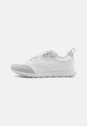 White and light gray low-top sneaker with laces, pull tab at heel, and "HUGO" logo on the side panel.