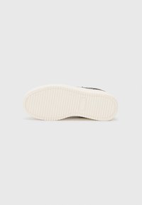 Semelle de sneaker en caoutchouc blanc avec un motif de texture. Le design présente une forme arrondie et une base plate pour la stabilité.