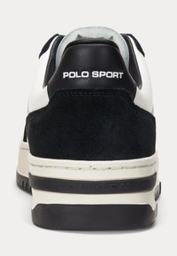 Mustat mokka- ja nahkasneakerit, joissa on valkoinen 'POLO SPORT' -brändäys. Pinnassa on tekstuuri ja kontrastivärinen, pehmustettu pohja.