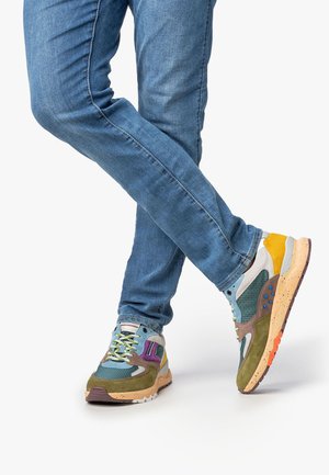Mehrfarbiger Sneaker aus Mesh- und Wildledermaterialien, mit einer Mischung aus Blau, Grün, Gelb und lila Akzenten. Strukturierten Sohle in Braun und Orange.