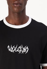 Zwarte T-shirt met een witte geribde ronde hals en een witte grafische print op de voorkant. De stof lijkt zacht en soepel te zijn.