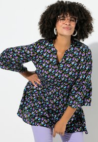 Blomstret bluse med sort baggrund, der har lilla og blå blomster, V-udskæring og udvidede trekvartærmer. Letvægtsstof.