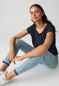 Blusa blu navy a maniche corte con scollatura a girocollo abbinata a jeans skinny azzurri, con orli sfilacciati e sneakers bianche.