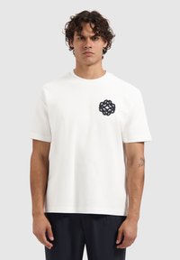 Witte katoenen t-shirt met korte mouwen en een ronde hals, met een donkerblauw geborduurd rond logo op de linkerborst.