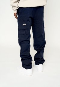 Pantalones cargo azul marino hechos de un tejido duradero, con múltiples bolsillos, un ajuste holgado y un logotipo bordado en el lateral.