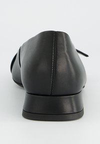 Chaussure plate en cuir noir avec bout arrondi, talon bas, texture lisse et détail subtil de coutures le long de l'arrière.