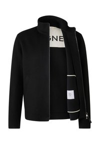 Sort stofjakke med høj krave, lynlåslukning foran og sidelommer. Indersiden viser en cremefarvet foring med logo print og detaljer.