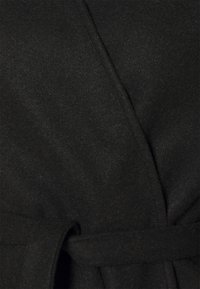 Černý kabát z vlněné směsi s obálkovým designem, který má pásek vpředu a měkkou texturovanou látku. Minimalistický vzhled s hladkým povrchem.
