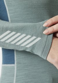 Jasnoniebieski sportowy top z teksturowanej dzianiny, z białym ukośnym paskiem na rękawie oraz kontrastującym niebieskim panelem akcentowym.