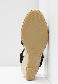 Sandale noire avec une semelle plateforme texturée, dotée d'une base en liège et d'une semelle extérieure en caoutchouc. Bride réglable avec détail en métal argenté. Taille 37.