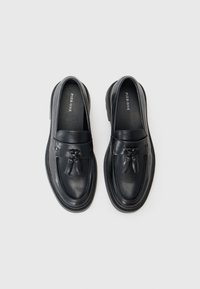 Black leather loafers with a smooth finish, tassel accents, and a thick textured sole. Brand name "PIER ONE" visible inside.