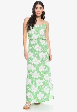 Vestido maxi con un patrón floral en verde y blanco, con una cintura ajustada, tirantes finos y una silueta fluida.