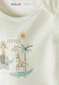 Bijeli dječji kombinezon s crtanim životinjama iz džungle uključujući lava, slona, žirafu, krokodila, palmu, sunce i tekst "mali džungla PRIJATELJI".