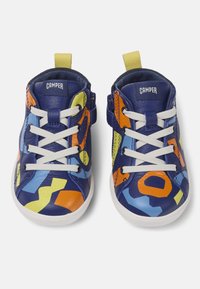 Zapatillas de cuero azul con patrones geométricos multicolores, cordones blancos y una lengüeta amarilla. Cuentan con un cierre lateral y suelas de goma.