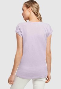 Lila Kurzarm-T-Shirt mit umgeschlagenen Ärmeln, aus weichem Baumwollmaterial, schmaler Schnitt und feinen Nähten entlang dem Saum.