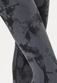 Leggings noirs avec un motif marbré dans des nuances de gris variées. Fabriqués à partir d'un tissu lisse et extensible avec un design près du corps.