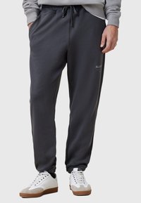 Donkergrijze, taps toelopende sweatpants met een elastische tailleband en koord. Zachte stof met zijzakken en een logo-detail op de linkerdij.