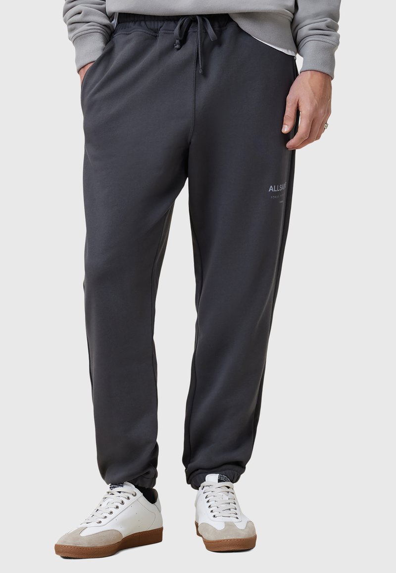 Donkergrijze, taps toelopende sweatpants met een elastische tailleband en koord. Zachte stof met zijzakken en een logo-detail op de linkerdij.