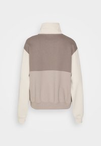 Sudadera color bloqueada en beige y marrón con un alto cuello, puños y dobladillo acanalados, fabricada en suave algodón y con un corte relajado.