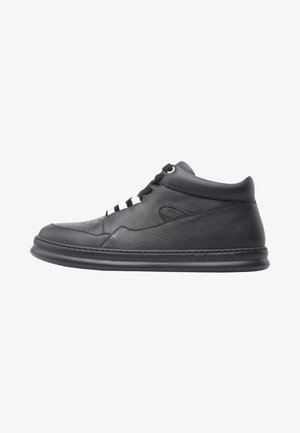 Czarny skórzany sneaker za kostkę z sznurowaniem z przodu, wyściełanym kołnierzem i grubą, wyściełaną podeszwą, pokazany na białym tle z profilu.