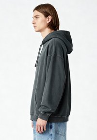 Felpa grigia carbone con tasca frontale, cappuccio con cordini e polsini a coste. Tessuto morbido con una vestibilità comoda.