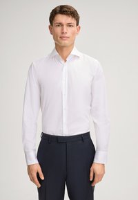 Witte overhemden met een spread-kraag, lange mouwen en knoopsluiting, gecombineerd met donkere, stijlvolle broeken die een slanke pasvorm tonen.