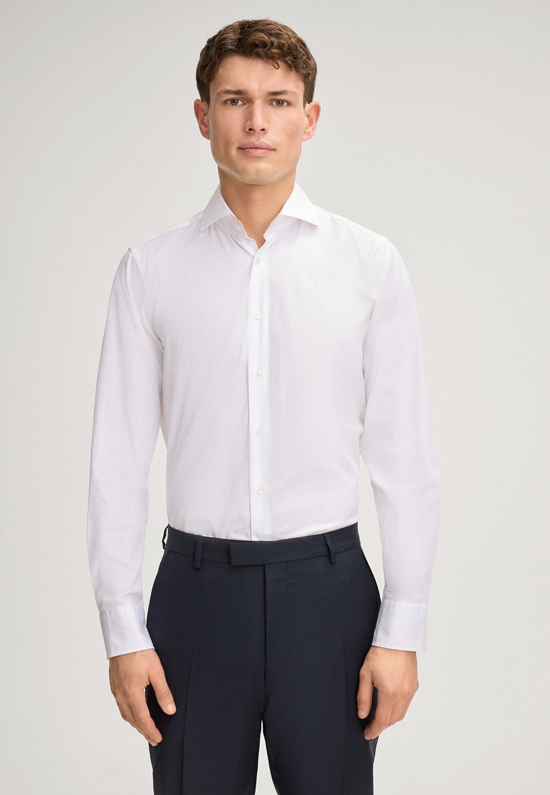 Witte overhemden met een spread-kraag, lange mouwen en knoopsluiting, gecombineerd met donkere, stijlvolle broeken die een slanke pasvorm tonen.