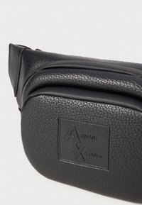 Bolsa de cintura preta em couro texturizado com fecho de zipper e patch em relevo do logótipo Armani Exchange na parte da frente.