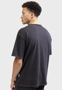 Sort, kortærmet t-shirt i bl�ødt stof. Har en afslappet pasform, rund halsudskæring og subtile slidte kantdetaljer.