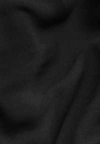 Musta kangas, jossa on sileä rakenne, esittää hienovaraisia aaltoja ja taitoksia, korostaen sen keveyttä ja virtaavaa luonteenpiirrettä.