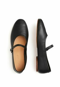 Svarta läder Mary Jane-lägenheter med rund tå och en liten klack. Har ett rem med en rund spänne och en slät, matt yta.