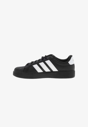 Sort lav sko med hvide Adidas tre striber og hvid hælfane, sorte snørebånd og tyk sort sål, sidevisning.