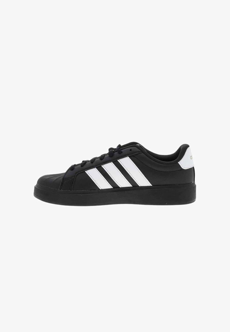 Baskets basses noires avec trois bandes blanches Adidas et languette de talon blanche, lacets noirs et semelle noire épaisse, vue de côté.