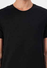 Tricou negru din bumbac cu guler rotund și mâneci scurte. Prezintă o textură netedă și un design simplu, într-o singură culoare.